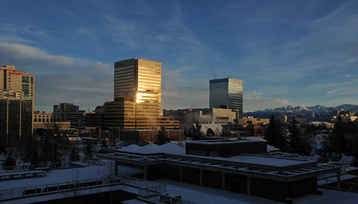 Sunrise reflected from oil buildings, Chugach mountain range in background, Anchorage, Alaska