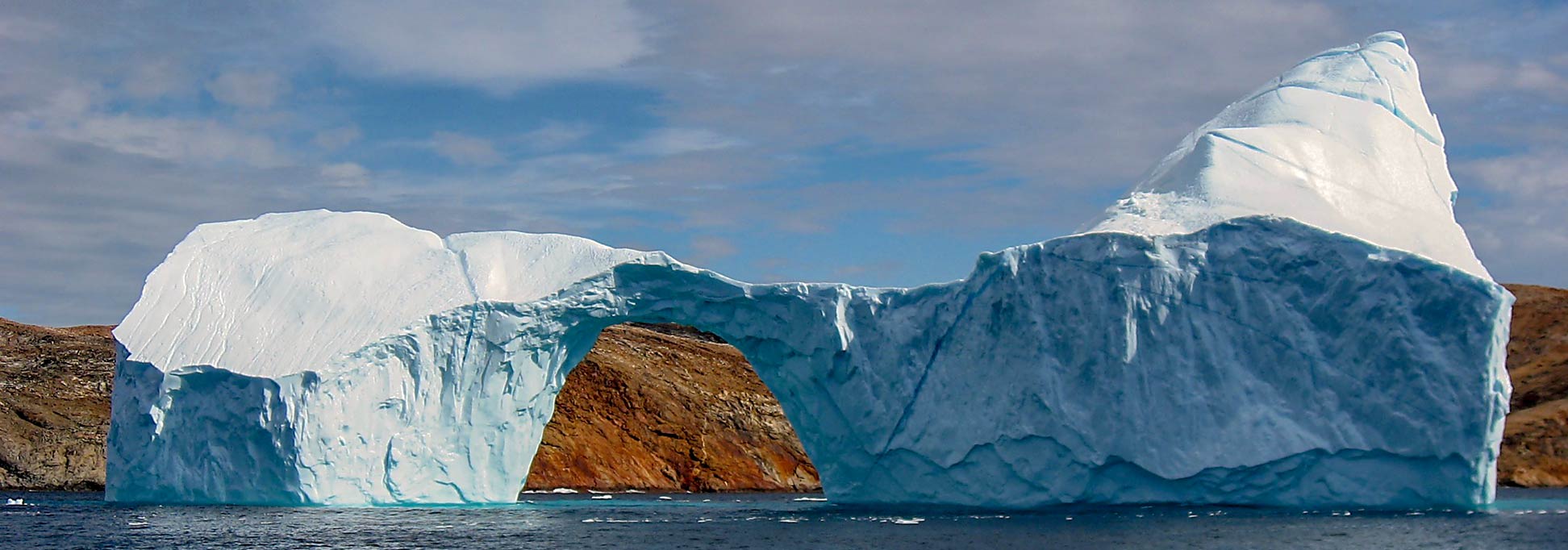 Iceberg with a hole in the strait between Langø and Sanderson Hope