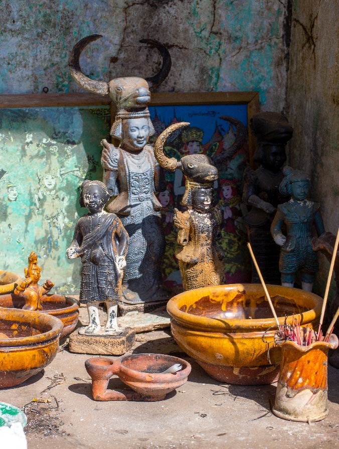 A Burmese shrine with horned idols and incense sticks