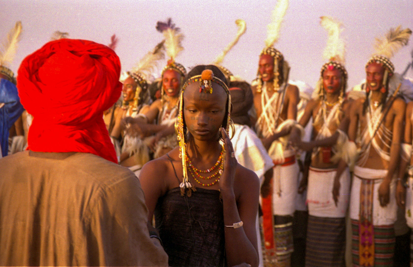 A young Wodaabe girl shyly assesses the participants of the Gerewol courtship festival.