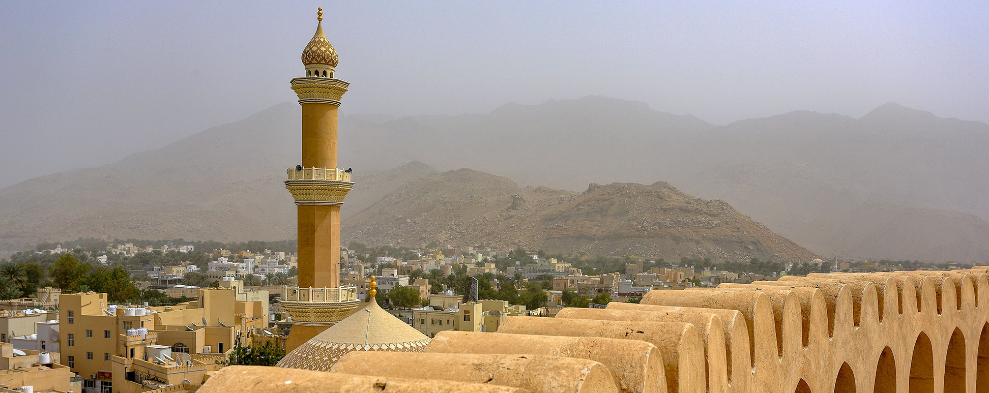 Minaret of the Friday Mosque, and part of Nizwa Fort in Nizwa, Oman