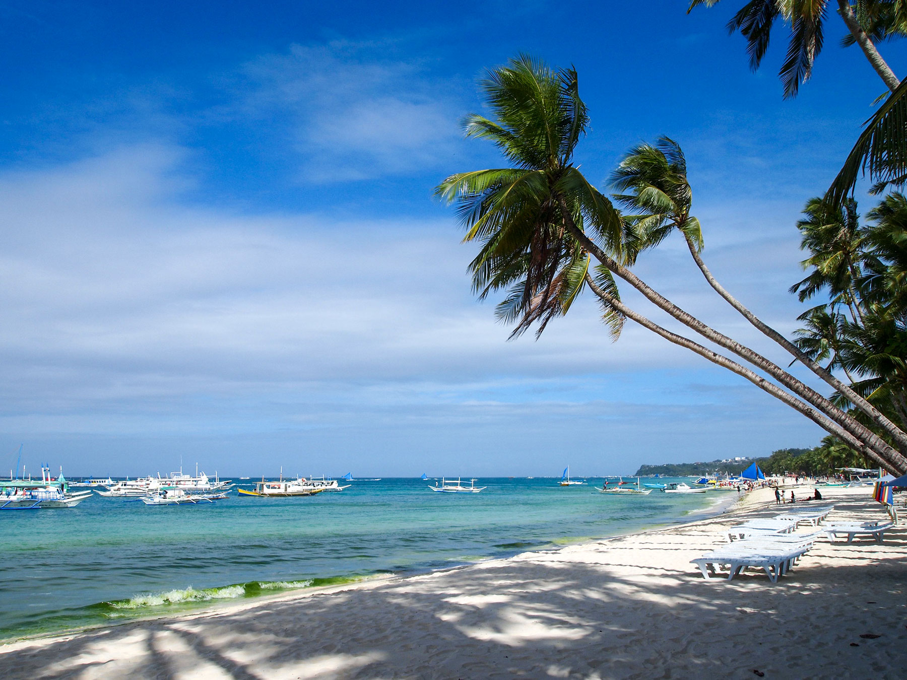 The White Beach on Boracay with moored bangkas and paraws, traditional Filipino outrigger boats.