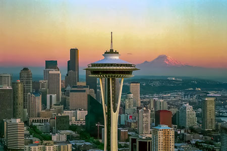 Seattle's Space Needle with skyline and Mount Rainier at sunset.