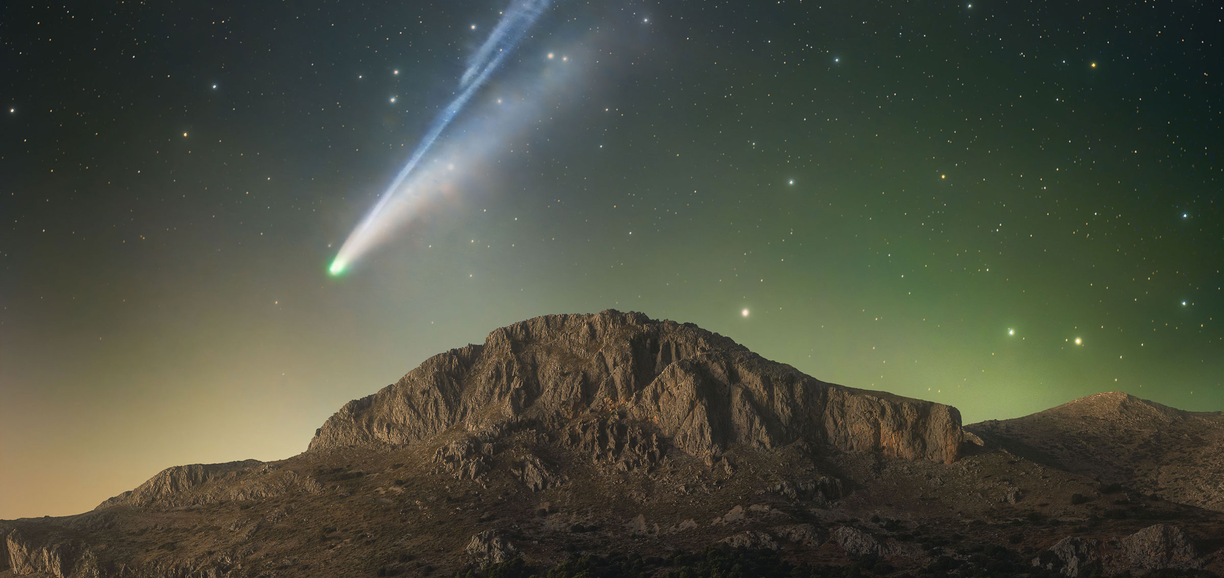 Comet Lemmon (C/2025 A6) A passing comet lights up the night sky over a mountain range in Spain.