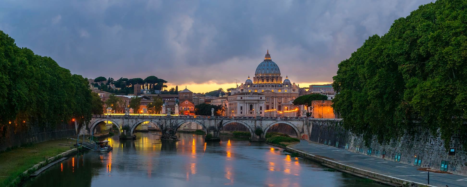Rome at dusk with the Sant'Angelo bridge over the Tiber river and St. Peter's Basilica